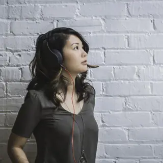 Listener in headphones against a brick wall