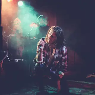 Singer holding a microphone on a smoky stage